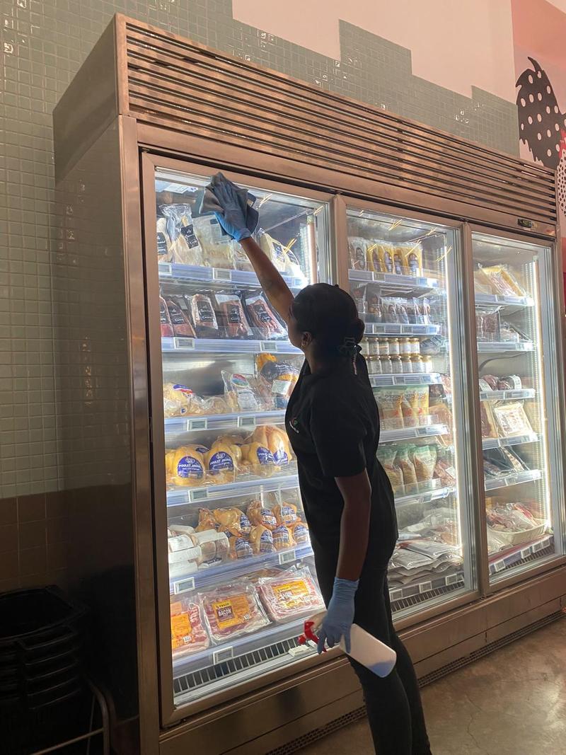 CleanLee cleaner wiping the glass doors of a display chiller at an F&B outlet