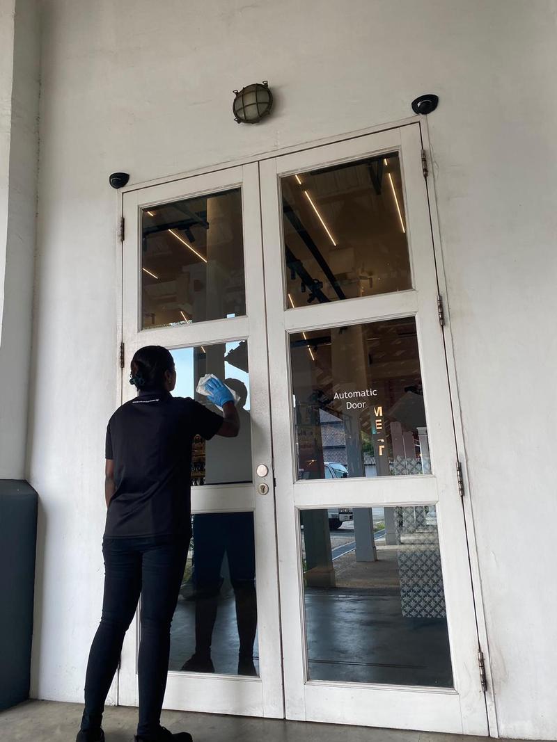 Cleaner wiping the glass panels of a white double entrance door