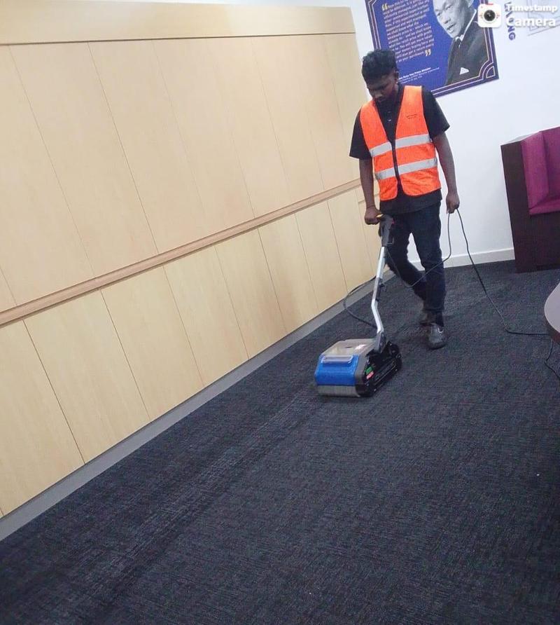 Cleaner deep-cleaning office carpet with a compact carpet scrubbing machine