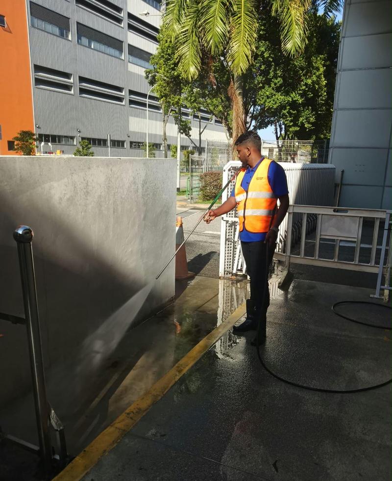 CleanLee cleaner pressure-washing an exterior wall and ramp of a commercial building