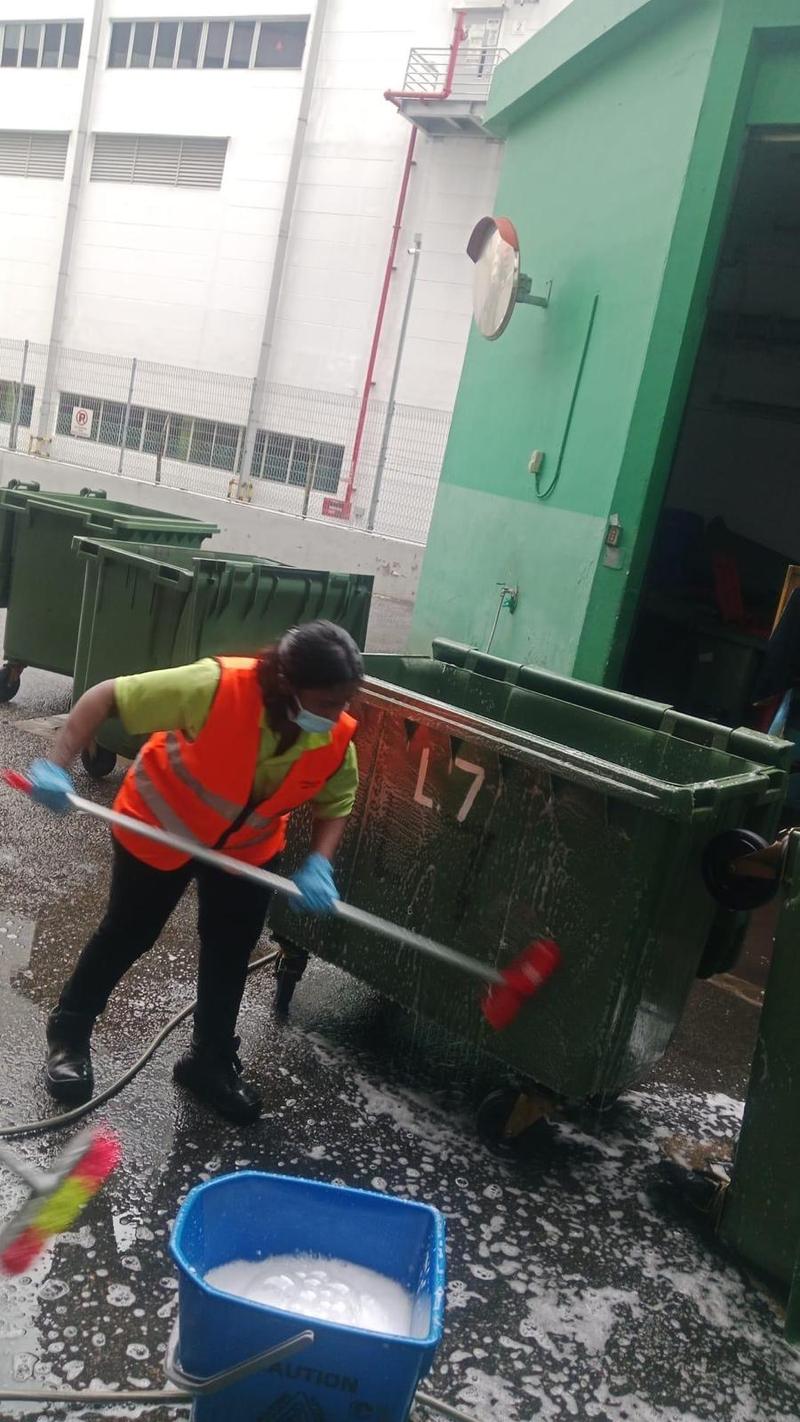 CleanLee cleaner washing large refuse bins at a bin centre with a brush and soapy water