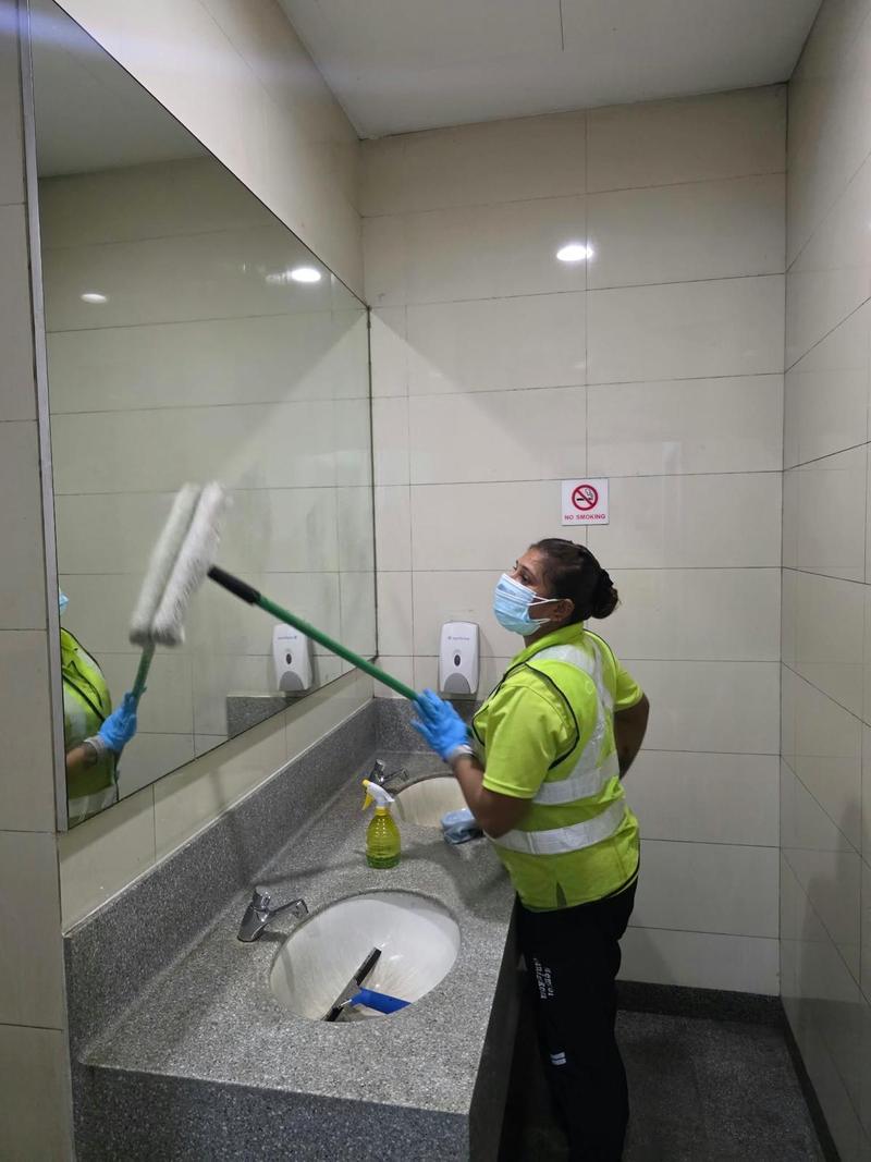 Cleaner in a face mask using an extendable applicator to clean a washroom mirror